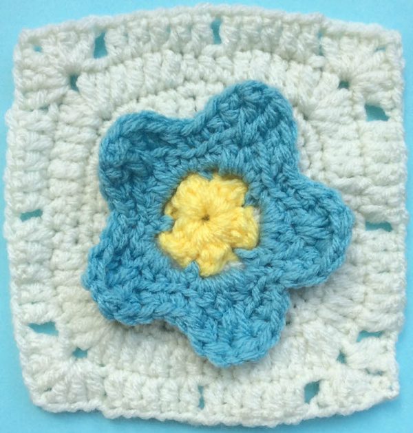 Crochet pattern: Forget-me-not Square in Red Heart With Love by Underground Crafter | This simple pattern features a dimensional flower at the center. The last round is perfect for the join-as- you-go method. It’s one of two squares used in the Picking Flowers Pillow.