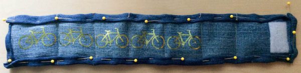 Semi-Quilted Upcycled Denim Bike Pant Leg Cuff, sewing tutorial by Underground Crafter | Wearing a bike cuff is a great way to keep your pant leg out of your bike’s chain so you can avoid damaging your clothes or having an accident. This simple, lightly quilted project is easy enough for a sewing or quilting beginner. This project features foil iron-on for decoration, iron-on fasteners, and binding made from the back piece. Instructions are provided for customizing the size.