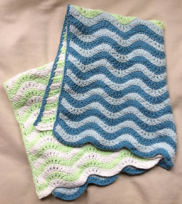 Free crochet pattern: Teeny Ripples preemie/stroller blanket in Lion Brand Feels Like Butta yarn by Underground Crafter | folded blanket on bed