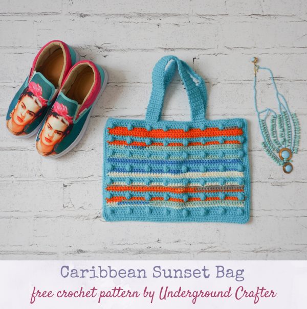 Caribbean Sunset Bag, free crochet pattern in Paintbox Yarns Chunky Pots and Simply Chunky yarns by Underground Crafter | flat lay photo of textured, striped bobble crochet bag on faux brick background with Frida Kahlo shoes and dangling stone necklace